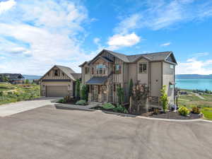 View of front of house featuring board and batten siding, stone siding, driveway, and a water view