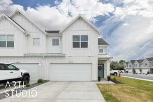 View of front of home with board and batten siding, a garage, concrete driveway, a front lawn, and a shingled roof
