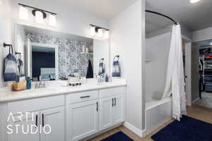Full bath with wood finished floors, double vanity, shower / bath combo, and ensuite bathroom