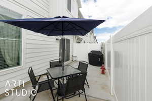 View of patio with fence, outdoor dining area, and grilling area