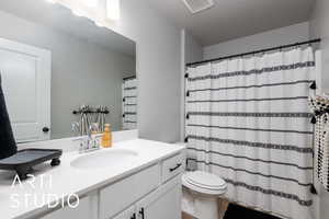 Bathroom featuring toilet, vanity, and curtained shower
