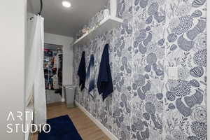 Bathroom with wood finished floors, baseboards, and wallpapered walls