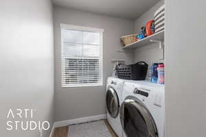 Washroom with washer and clothes dryer, baseboards, and light wood-type flooring