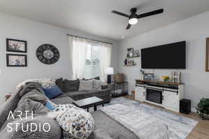 Living area with a ceiling fan, wood finished floors, and baseboards