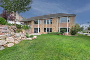 Back of property featuring a lawn, brick siding, and a patio