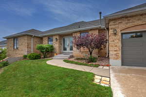 View of front facade with french doors, brick siding, a front lawn, a garage, and roof with shingles