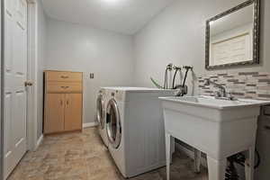 Washroom featuring light stone finish floors, baseboards, and washer and clothes dryer