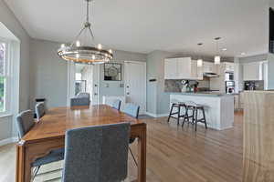 Dining space featuring a chandelier, light wood-type flooring, baseboards, and recessed lighting