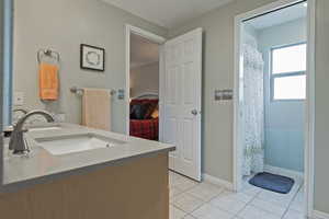 Bathroom featuring tile patterned flooring, double vanity, curtained shower, and baseboards