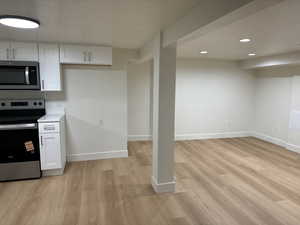 Kitchen featuring appliances with stainless steel finishes, white cabinetry, baseboards, light wood finished floors, and recessed lighting