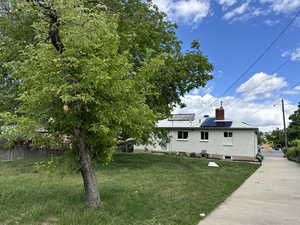 View of side of home featuring solar panels, a yard, a chimney, and brick siding