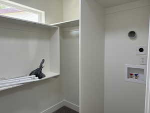 Washroom with hookup for an electric dryer, hookup for a washing machine, and baseboards