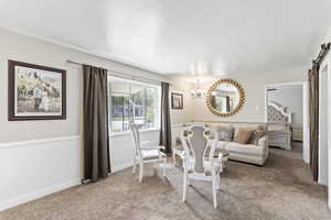 Living area with a barn door, a chandelier, carpet, and accent walls