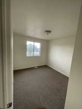 Empty room featuring dark colored carpet and baseboards