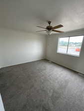 Carpeted empty room featuring ceiling fan and baseboards