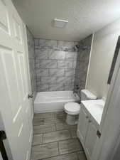 Full bathroom with vanity, toilet, tub / shower combination, and a textured ceiling