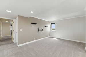 Spare room with light colored carpet, baseboards, and crown molding