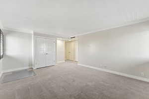 Unfurnished bedroom featuring crown molding, carpet flooring, and baseboards