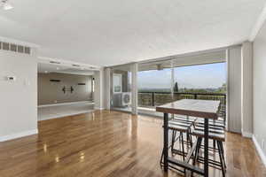 Unfurnished room featuring ceiling fan, healthy amount of natural light, floor to ceiling windows, baseboards, and wood finished floors