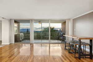 Dining space with floor to ceiling windows, wood finished floors, a ceiling fan, crown molding, and baseboards