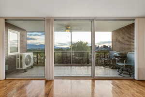 Doorway featuring expansive windows, wood finished floors, ac unit, and ceiling fan