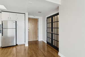 Kitchen featuring freestanding refrigerator, wood finished floors, white cabinets, and baseboards