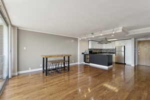 Kitchen featuring freestanding refrigerator, dark countertops, crown molding, white cabinetry, and a peninsula
