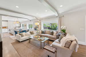 Living area with a chandelier, light wood-style floors, recessed lighting, beamed ceiling, and baseboards