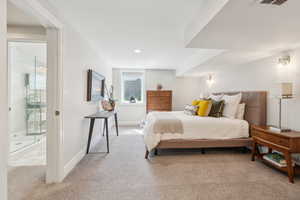 Carpeted bedroom featuring baseboards, recessed lighting, and ensuite bath