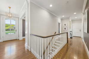 Hall featuring an upstairs landing, a chandelier, wood finished floors, crown molding, and recessed lighting