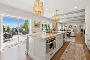 Kitchen featuring a sink, stainless steel appliances, open floor plan, a chandelier, and white cabinetry