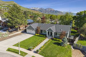 View of front of property featuring a mountain view, a garage, concrete driveway, a chimney, and a shingled roof