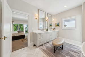 Ensuite bathroom with double vanity, marble finish floors, recessed lighting, and baseboards