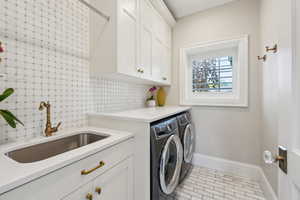 Washroom featuring cabinet space, separate washer and dryer, baseboards, and brick patterned floors