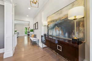 Corridor with wood finished floors, baseboards, ornamental molding, and recessed lighting