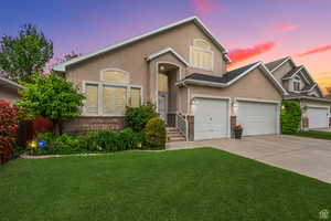 View of front of house with stucco siding, driveway, a lawn, and an attached garage
