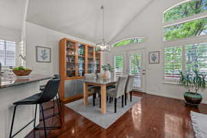 Dining room featuring dark wood-style flooring, baseboards, and high vaulted ceiling