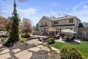 Rear view of house with fence, a patio, water features, an outdoor living space, and solar panels