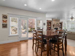 Dining area with a ceiling fan, recessed lighting, baseboards, light wood finished floors, and a large fireplace