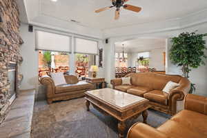 Living room with arched walkways, ceiling fan, a chandelier, and a fireplace
