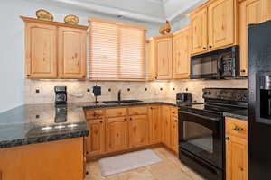 Kitchen with black appliances, a sink, tasteful backsplash, and light brown cabinets