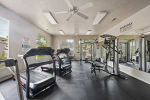Exercise room featuring ceiling fan, baseboards, and a textured ceiling