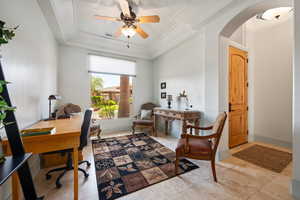 Home office featuring arched walkways, ceiling fan, and a tray ceiling