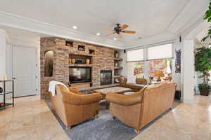 Living room featuring a ceiling fan, a fireplace, a tray ceiling, recessed lighting, and baseboards