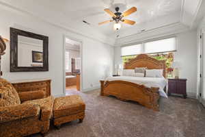 Bedroom featuring a raised ceiling, carpet flooring, ensuite bath, baseboards, and ceiling fan