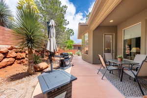 View of patio with fence, outdoor dining area, and a grill