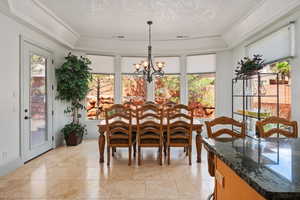 Dining area with a chandelier, plenty of natural light, stone tile floors, and a raised ceiling