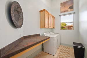 Laundry room with cabinet space, independent washer and dryer, and baseboards