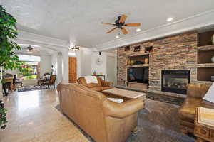 Living room with ceiling fan, arched walkways, a stone fireplace, recessed lighting, and tile patterned flooring