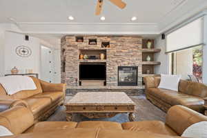 Carpeted living area with a ceiling fan, a stone fireplace, and recessed lighting